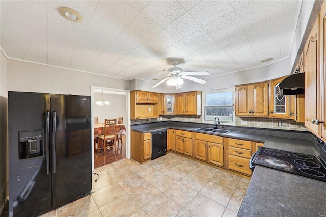 kitchen with brown cabinetry, dark countertops, a sink, and black appliances