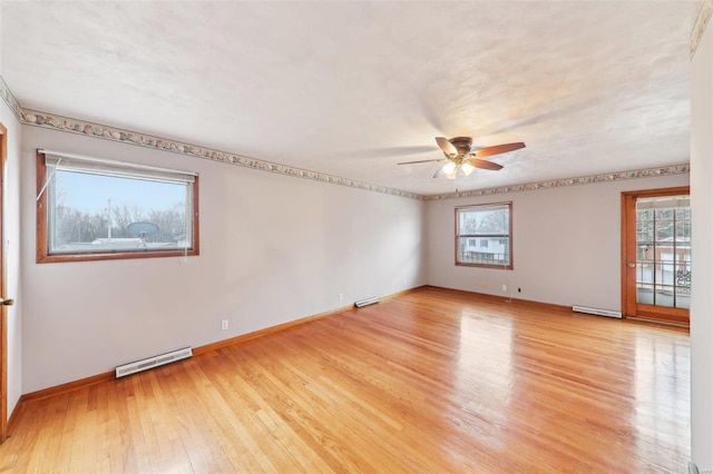 spare room with light wood finished floors, visible vents, baseboard heating, a ceiling fan, and baseboards