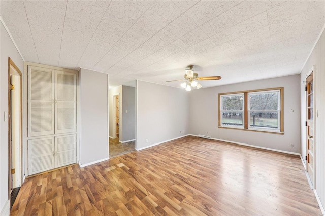 unfurnished bedroom featuring ceiling fan, a closet, baseboards, and wood finished floors