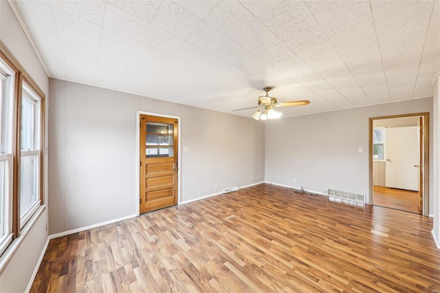 empty room featuring light wood-style floors, visible vents, baseboards, and a ceiling fan