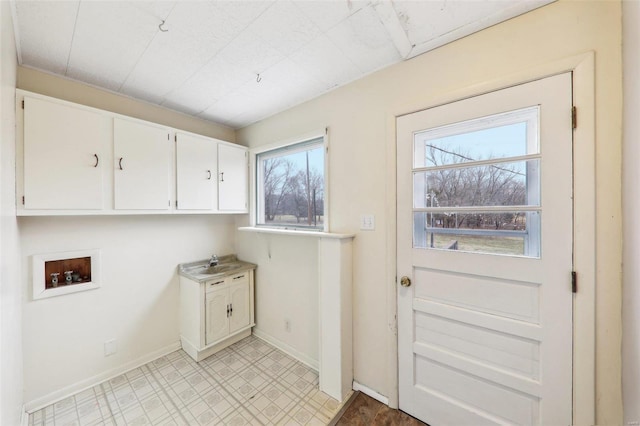 washroom featuring light floors, hookup for a washing machine, cabinet space, a sink, and baseboards