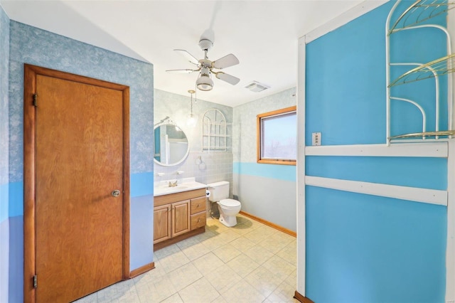 bathroom with visible vents, toilet, a ceiling fan, vanity, and baseboards