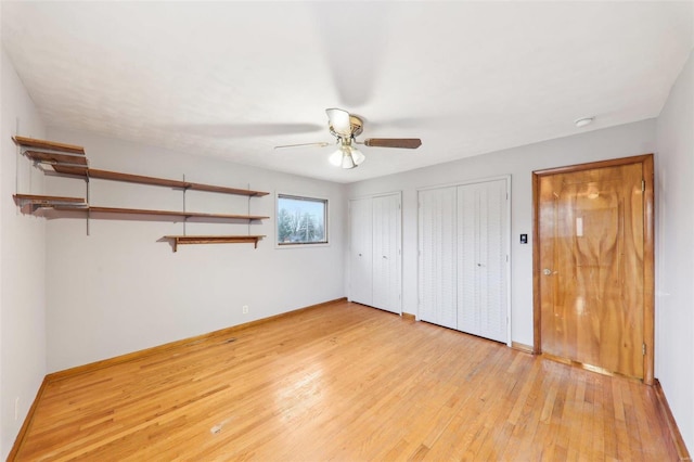 unfurnished bedroom featuring baseboards, light wood finished floors, and multiple closets