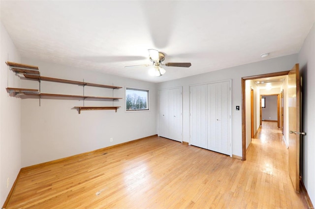 unfurnished bedroom with baseboards, a ceiling fan, light wood-style flooring, and multiple closets