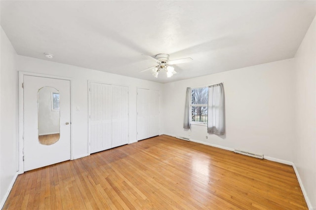 unfurnished bedroom with two closets, visible vents, light wood-style flooring, ceiling fan, and baseboards