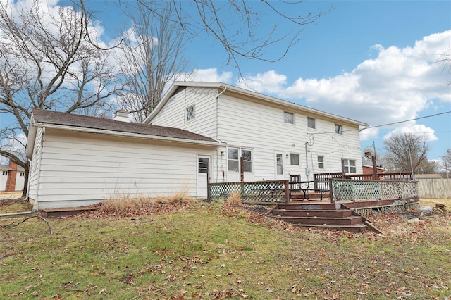 back of house with a chimney, a deck, and a lawn