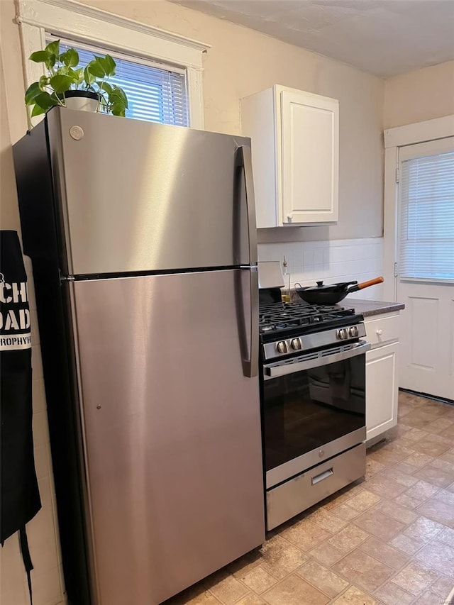 kitchen featuring stainless steel appliances, dark countertops, white cabinetry, and decorative backsplash