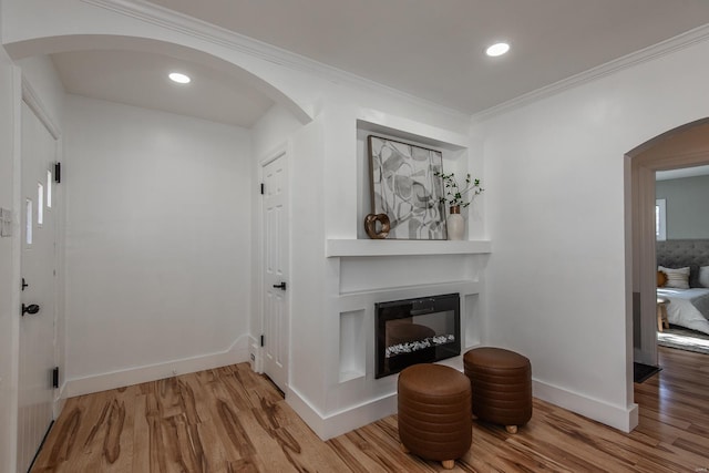 interior space with arched walkways, ornamental molding, baseboards, and wood finished floors