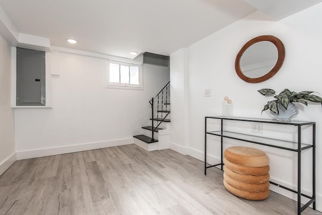 basement featuring stairway, wood finished floors, baseboards, electric panel, and a wall mounted air conditioner