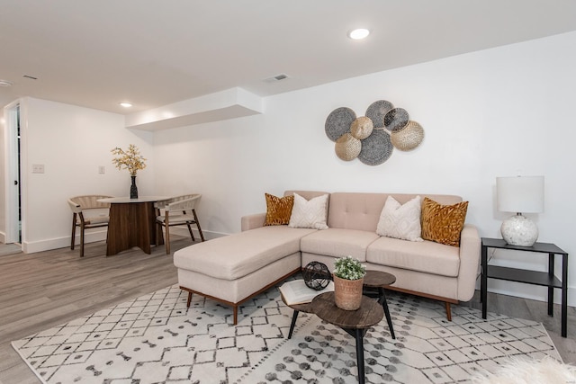 living area with recessed lighting, visible vents, baseboards, and light wood finished floors