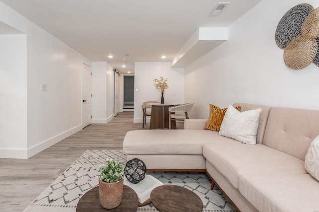 living area with light wood finished floors, visible vents, recessed lighting, and baseboards