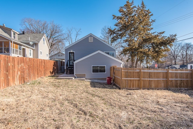 rear view of property featuring a yard and a fenced backyard