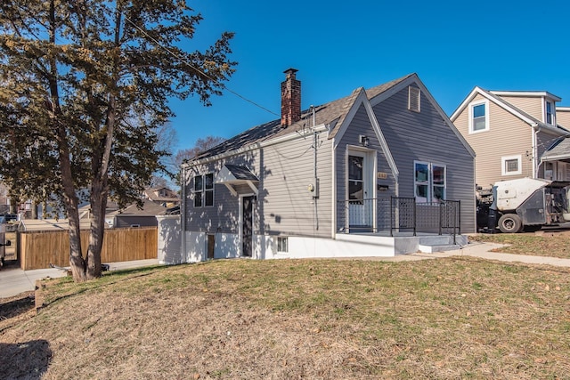 view of front of house with a chimney, a front yard, and fence