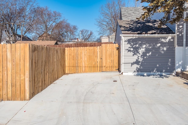 view of property exterior featuring roof with shingles, a patio, and fence