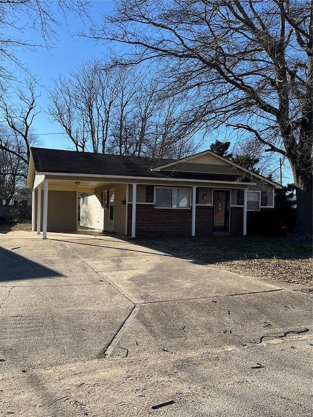 single story home with an attached carport, brick siding, and driveway