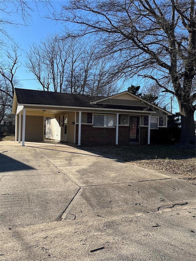 ranch-style home featuring an attached carport, concrete driveway, and brick siding