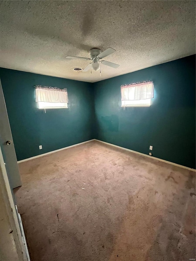 carpeted spare room with ceiling fan, a textured ceiling, and baseboards