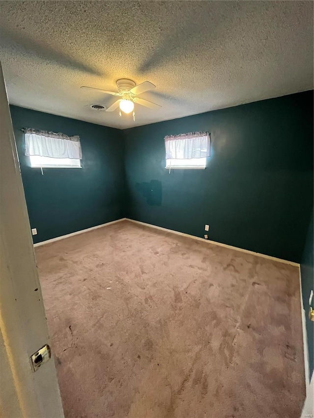 spare room with carpet, visible vents, ceiling fan, a textured ceiling, and baseboards