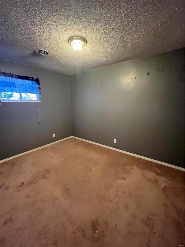 empty room featuring carpet floors, visible vents, baseboards, and a textured ceiling