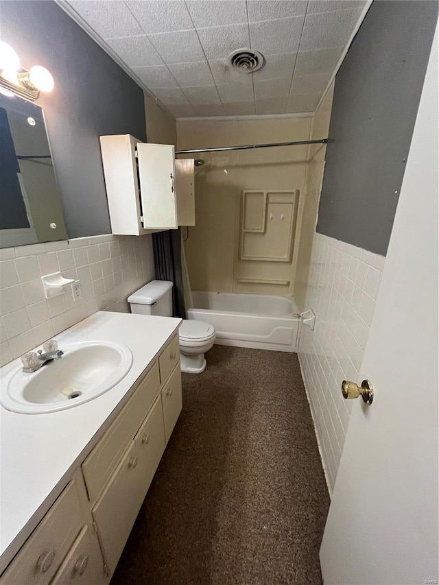 full bathroom featuring tile walls, visible vents, toilet, vanity, and  shower combination