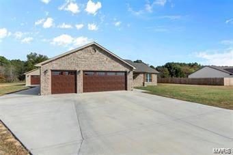 ranch-style house featuring a garage, concrete driveway, and a front lawn