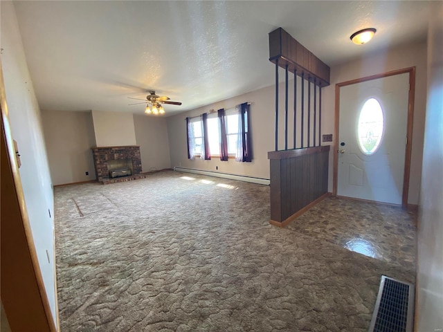 foyer entrance with visible vents, a ceiling fan, a baseboard heating unit, carpet floors, and a fireplace