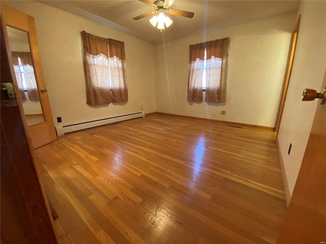 empty room featuring a baseboard radiator, hardwood / wood-style floors, and a ceiling fan