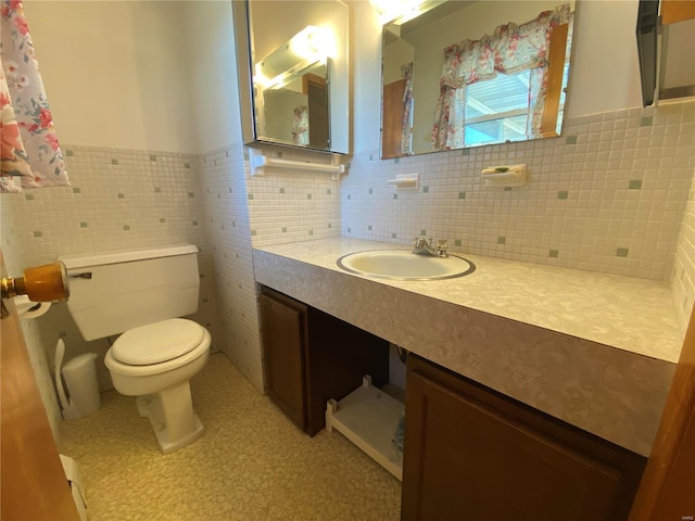 bathroom with vanity, tile walls, toilet, and a wainscoted wall