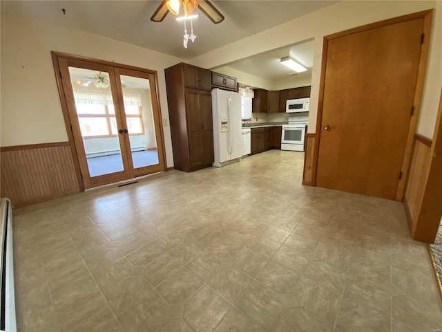 unfurnished living room with plenty of natural light, a ceiling fan, a wainscoted wall, and french doors