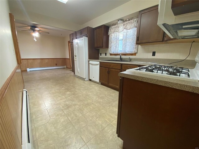 kitchen with a sink, light floors, white appliances, wainscoting, and baseboard heating