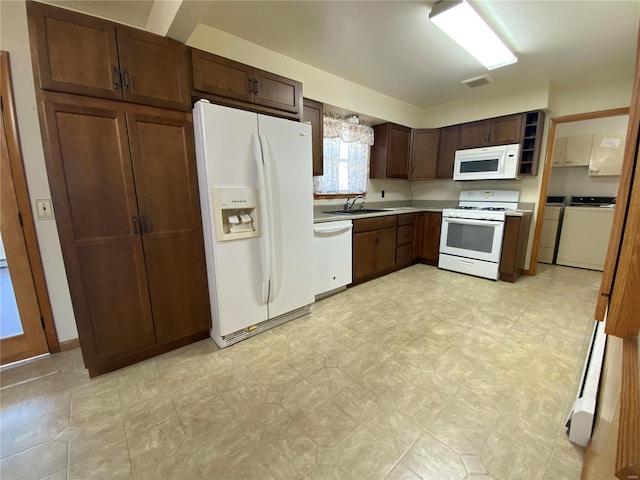 kitchen featuring white appliances, visible vents, separate washer and dryer, a sink, and light countertops