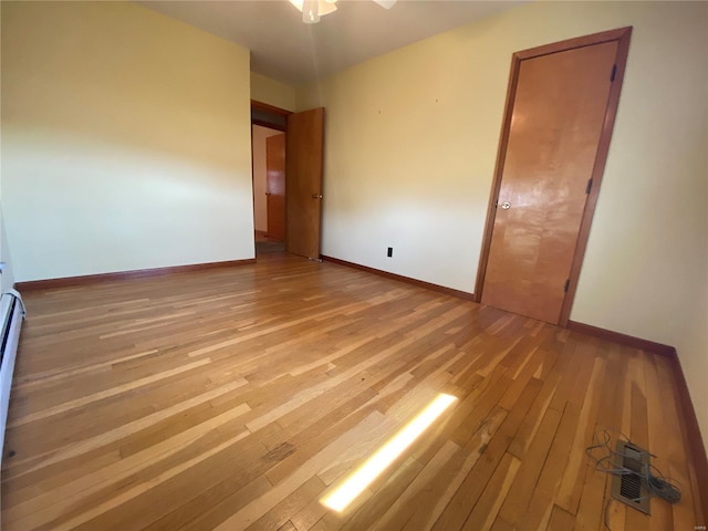 spare room featuring baseboards and light wood-style floors