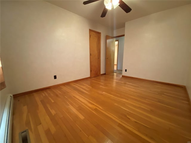 empty room with a ceiling fan, visible vents, baseboards, light wood-style floors, and a baseboard heating unit