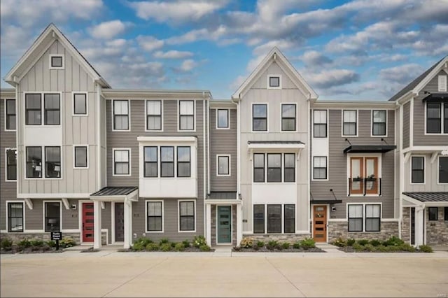 townhome / multi-family property with a standing seam roof, a residential view, metal roof, and board and batten siding