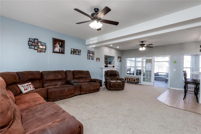 living area with tile patterned floors, baseboards, a ceiling fan, and carpet flooring