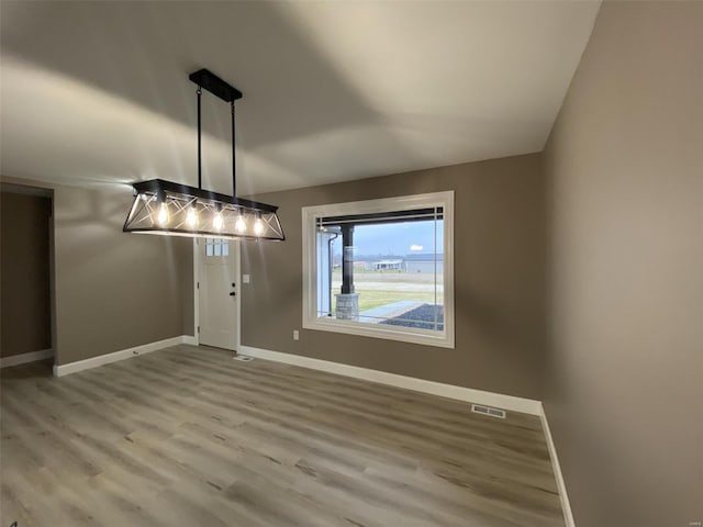 unfurnished dining area featuring visible vents, baseboards, and wood finished floors