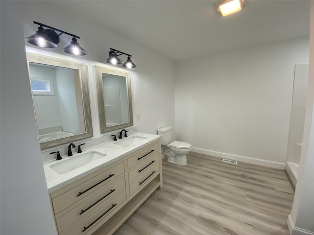 full bathroom featuring double vanity, wood finished floors, a sink, and baseboards