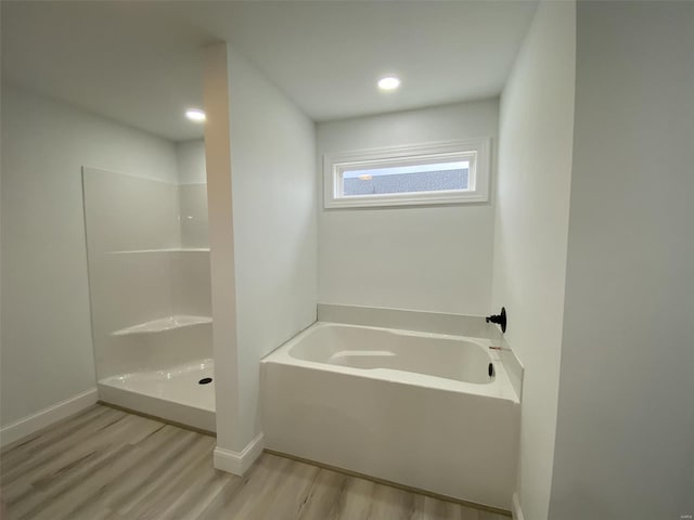 full bathroom with recessed lighting, wood finished floors, baseboards, a bath, and walk in shower