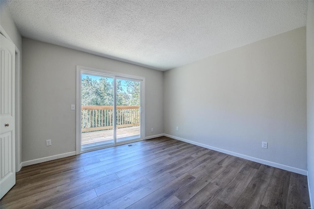 spare room featuring baseboards, dark wood finished floors, and a textured ceiling