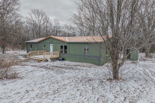 snow covered back of property with a deck