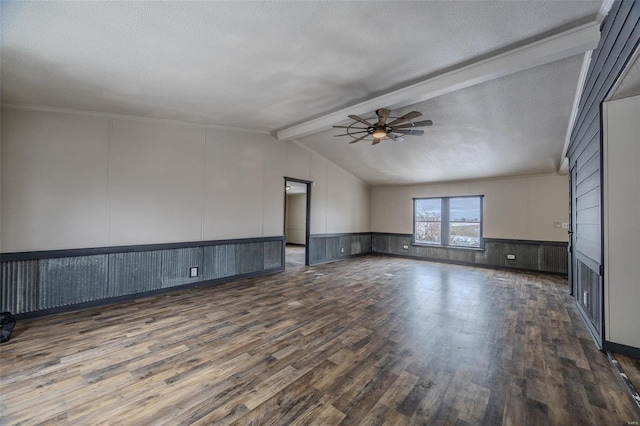 unfurnished room with dark wood-style flooring, a wainscoted wall, lofted ceiling with beams, a ceiling fan, and a textured ceiling