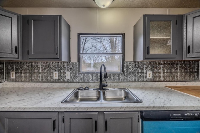 kitchen featuring dishwasher, gray cabinets, a sink, and light countertops