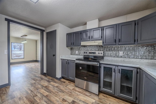 kitchen with light wood finished floors, tasteful backsplash, electric stove, a textured ceiling, and under cabinet range hood