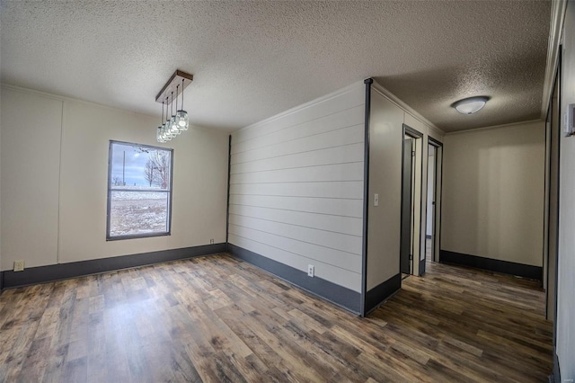 unfurnished room with dark wood-style floors, ornamental molding, a textured ceiling, and baseboards