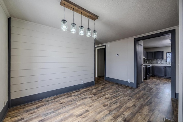 unfurnished dining area with dark wood-style floors, baseboards, and a textured ceiling