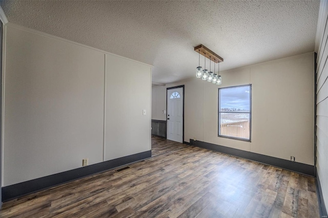 spare room with a textured ceiling, dark wood-type flooring, and crown molding