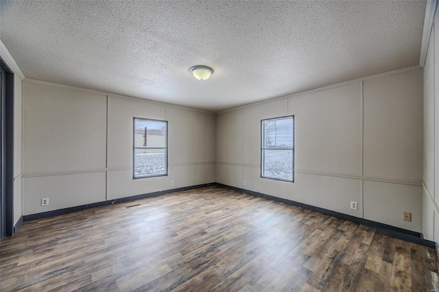 empty room featuring ornamental molding, plenty of natural light, and wood finished floors