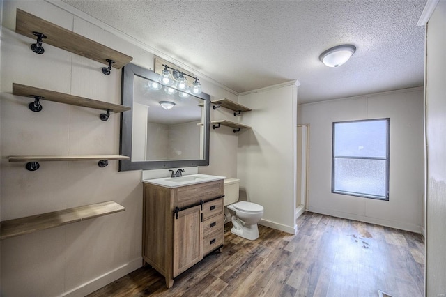 full bath featuring toilet, ornamental molding, wood finished floors, a textured ceiling, and vanity