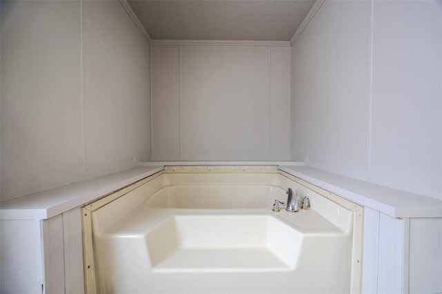 bathroom with ornamental molding, a garden tub, and a textured ceiling