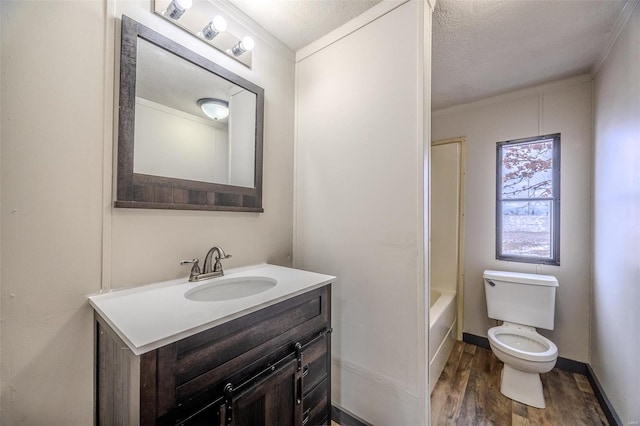 bathroom featuring crown molding, toilet, vanity, wood finished floors, and baseboards